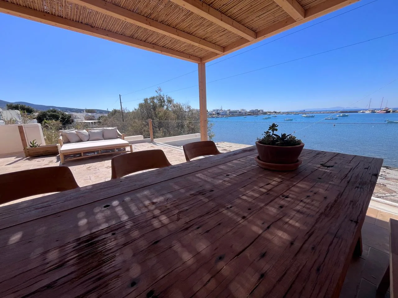 Covered terrace dining area with midday harbor view